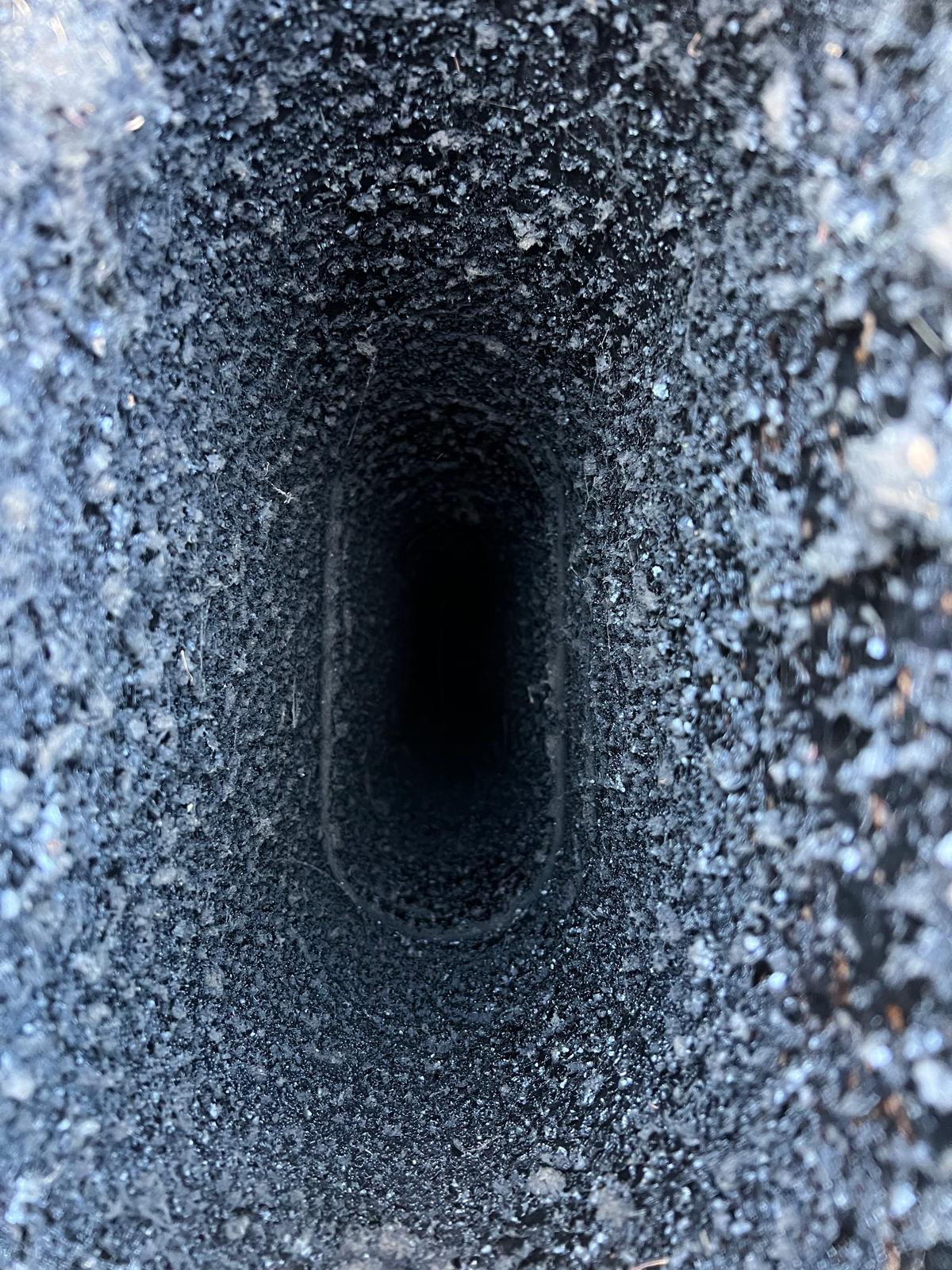 Close-up view inside a chimney flue showing heavy creosote buildup
