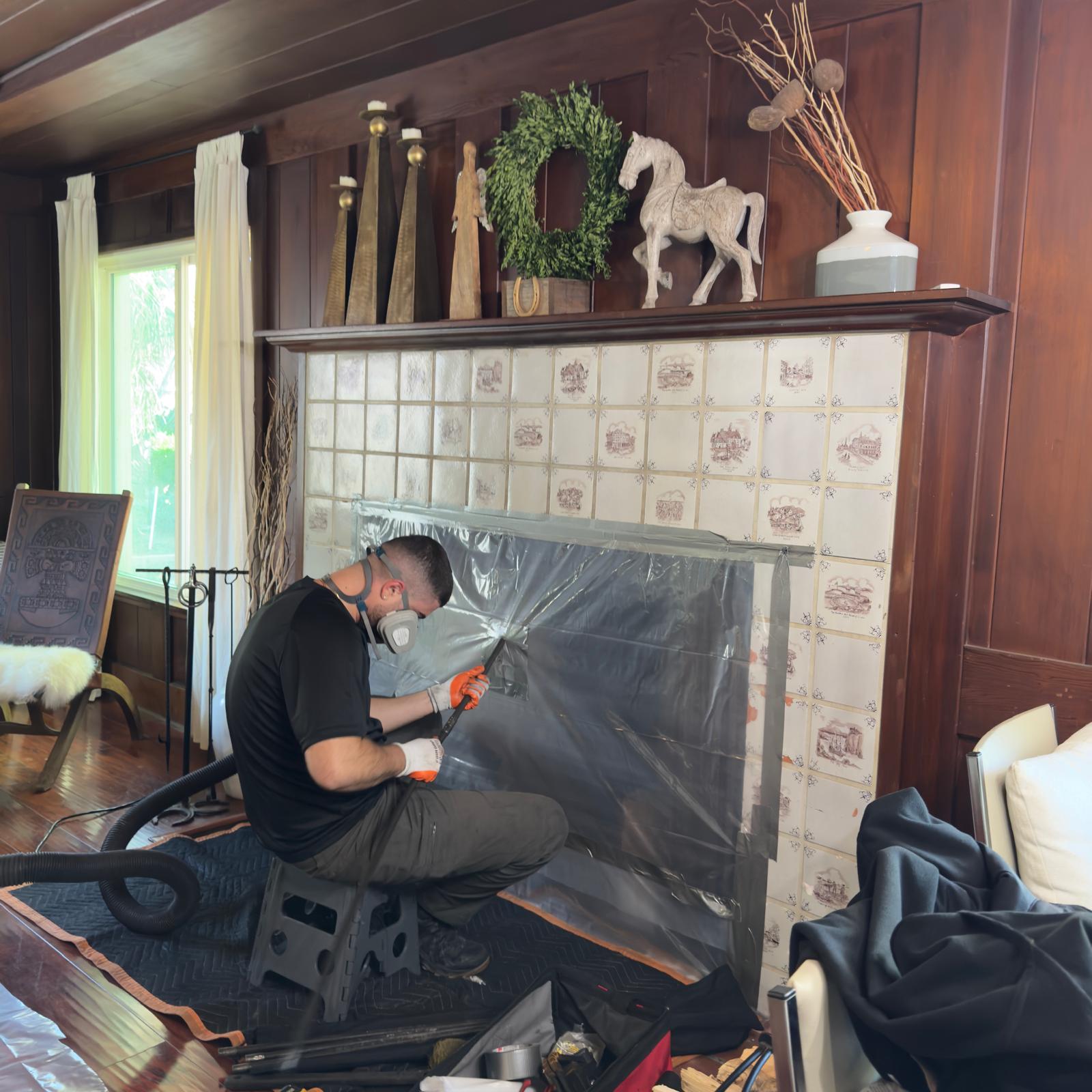 Technician cleaning soot from a residential fireplace opening