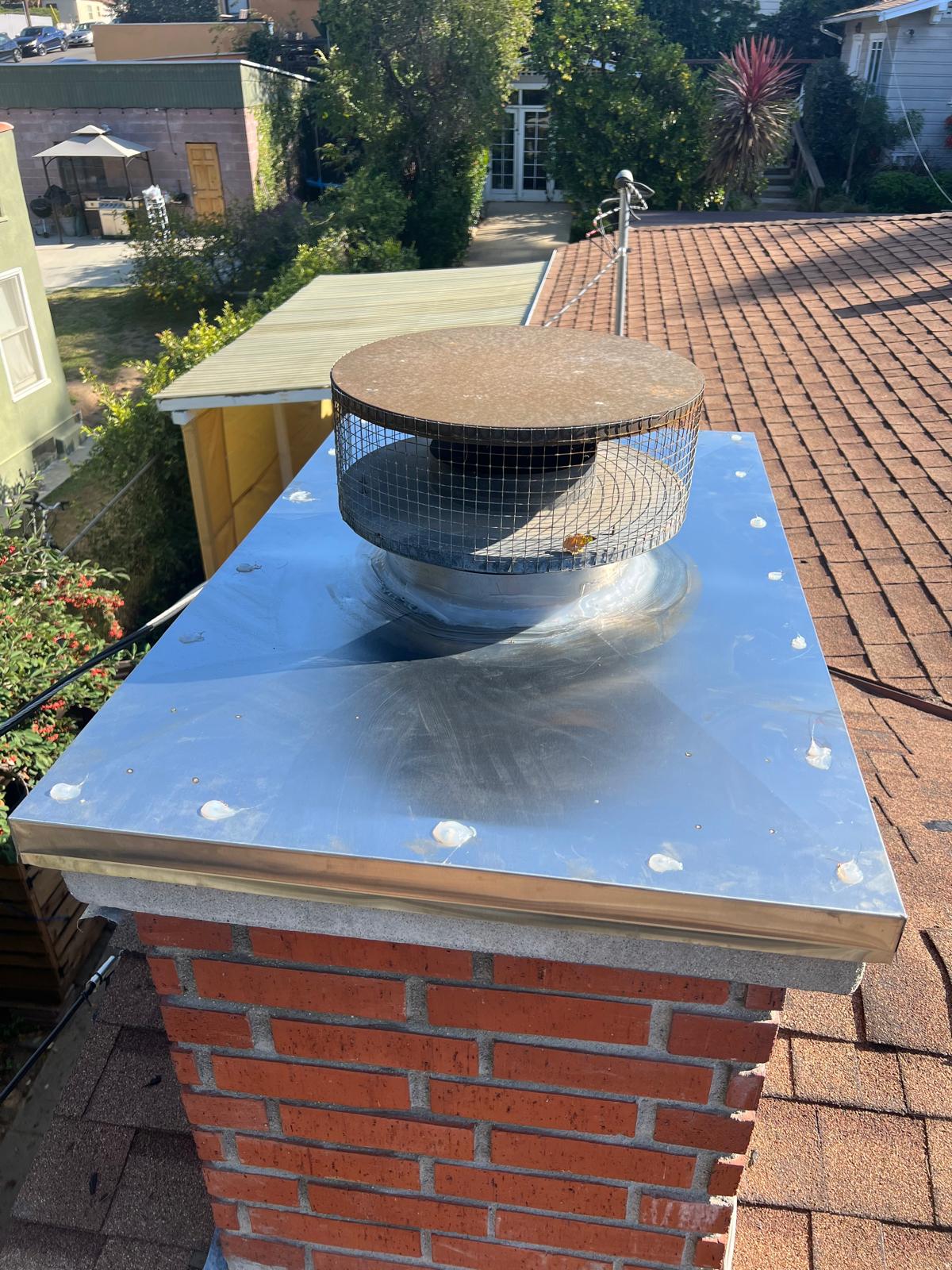 Close-up of a chimney cap and spark arrestor installed on a brick chimney